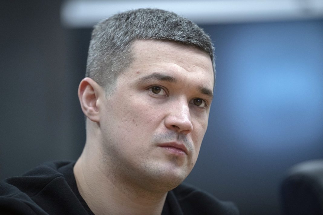 Muž s krátkými tmavými vlasy při veřejném vystoupení