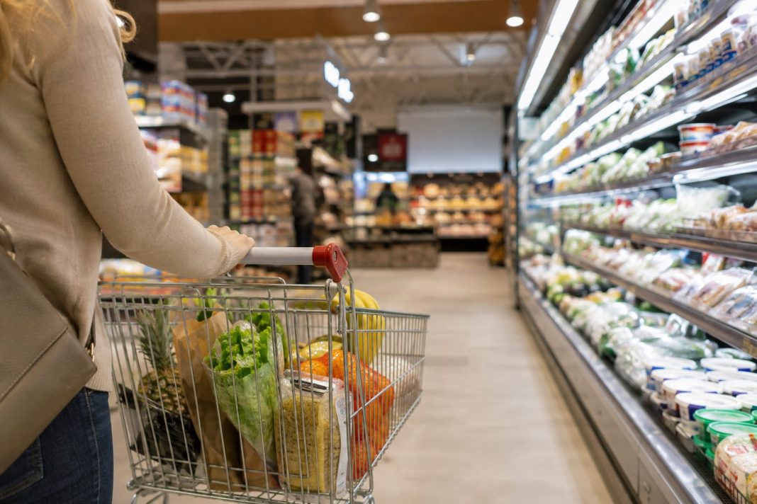 Zákaznice s nákupním vozíkem v uličce supermarketu s potravinami