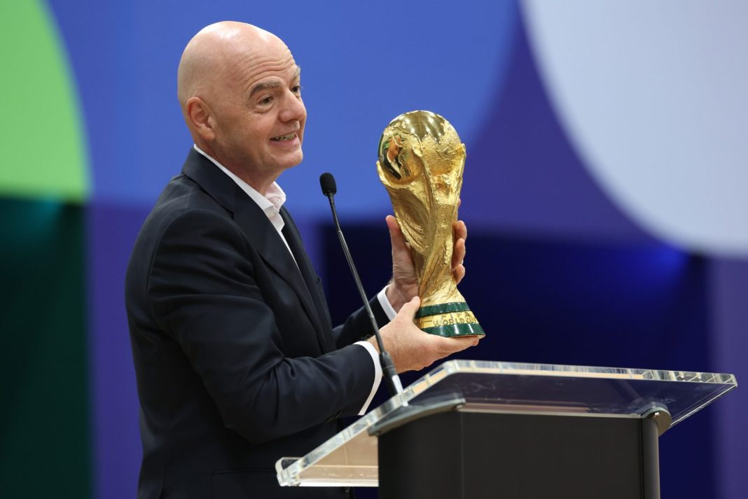 Gianni Infantino drží zlatou trofej mistrovství světa ve fotbale u řečnického pultu