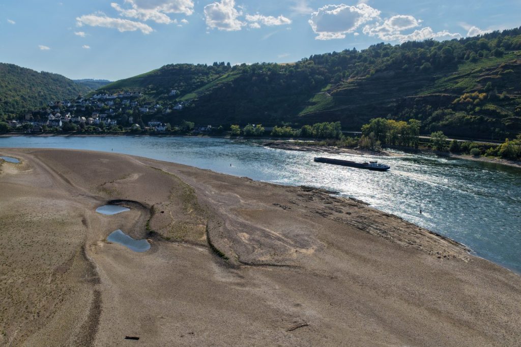 Nákladní loď pluje po Rýnu kolem rozsáhlého odkrytého říčního břehu při nízké hladině