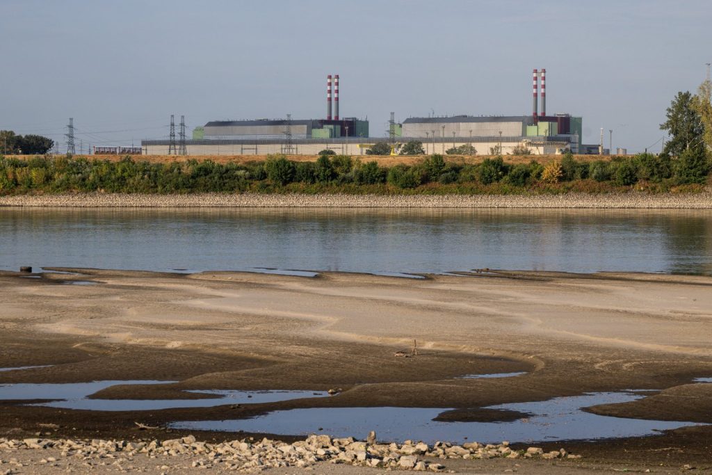 Jaderná elektrárna stojí za řekou s výrazně odkrytým korytem a nízkou hladinou vody