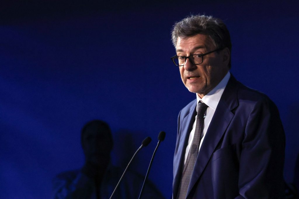 Italský ministr financí Giancarlo Giorgetti hovoří u řečnického pultu před tmavě modrým pozadím