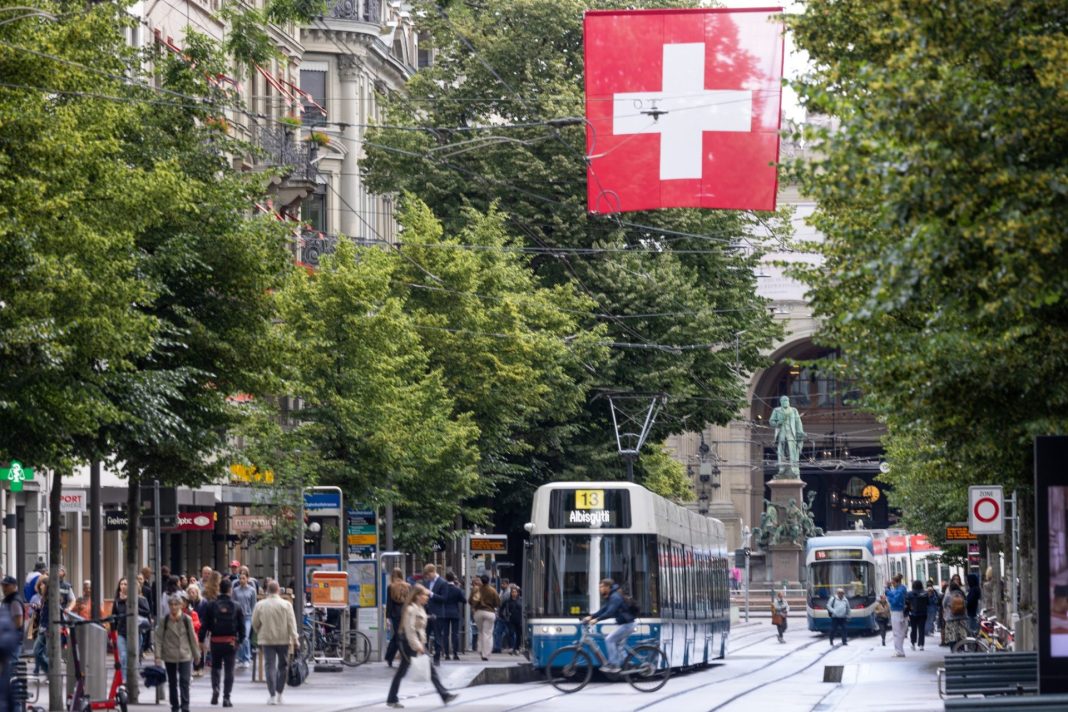 Městská ulice ve Švýcarsku s tramvají a velkou švýcarskou vlajkou