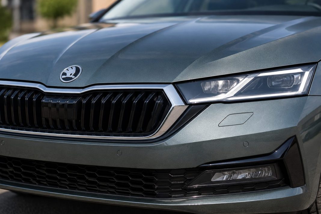 Detail přední části vozu Škoda s logem automobilky, maskou chladiče a světlometem