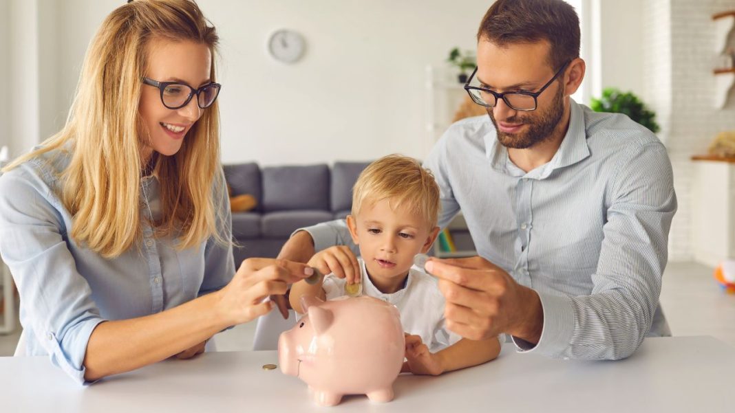 Finanční výchova dětí: rodiče s dcerou u stolu s prasátkem na úspory.