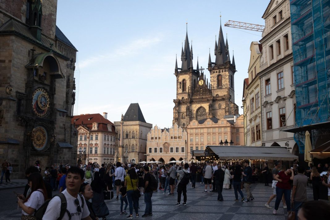 Lidé na Staroměstském náměstí v Praze s Týnským chrámem a orlojem v pozadí