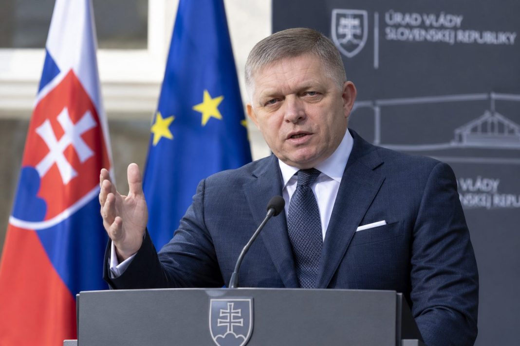 AI ilustrační zobrazení slovenského premiéra Roberta Fica při projevu před slovenskou a evropskou vlajkou