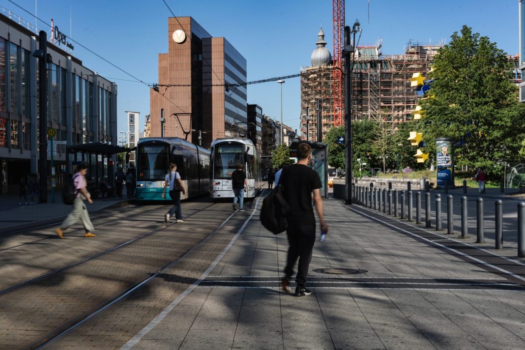 Městská ulice v Německu s tramvajemi, chodci a kancelářskými budovami